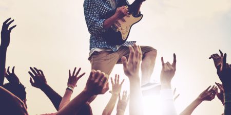 Closeup of diverse arms raised in live music concert